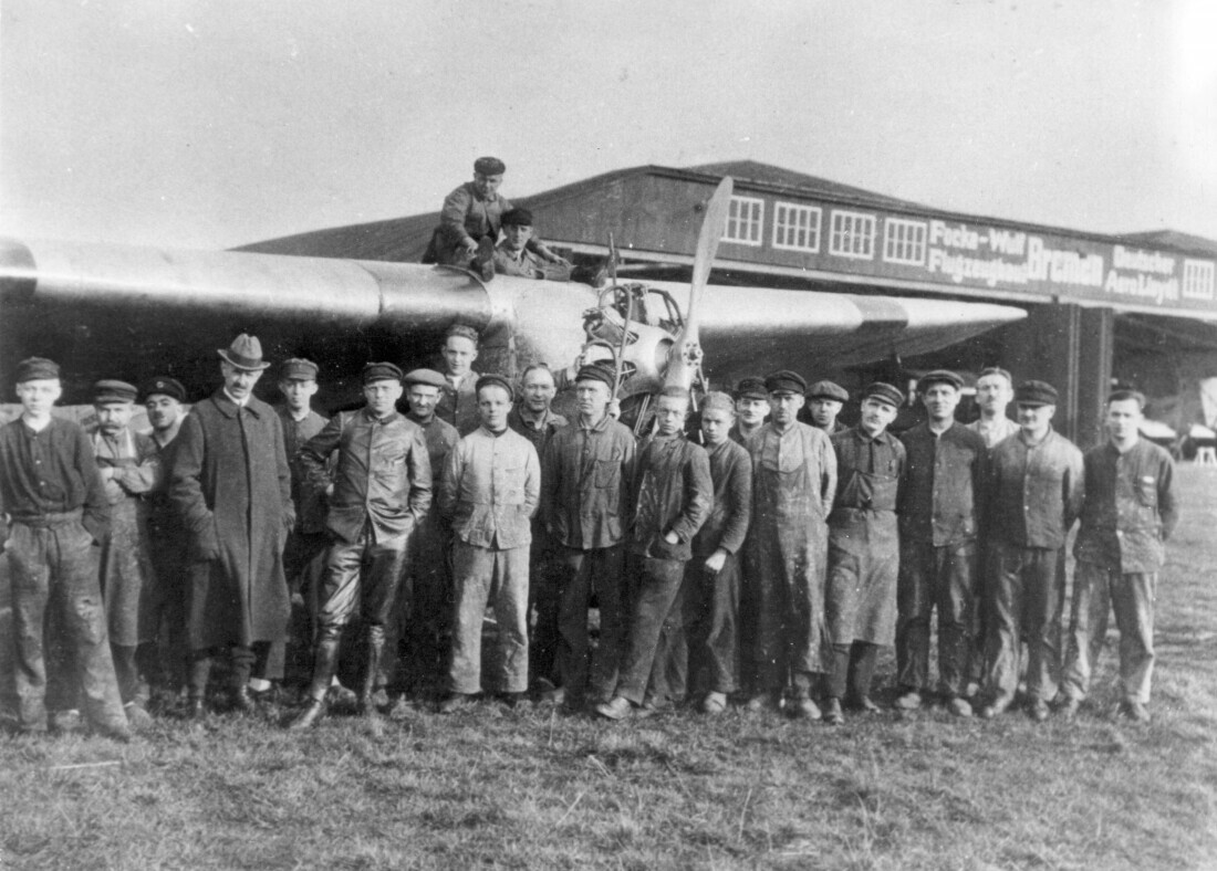 A group of men stand in front of an aeroplane
