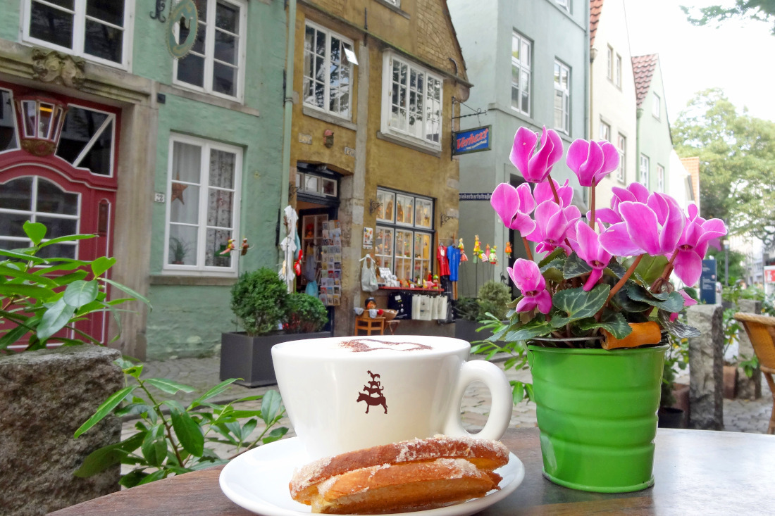 Ein Kaffee mit Gebäck vor Geschäften im Bremer Schnoor gezeigt