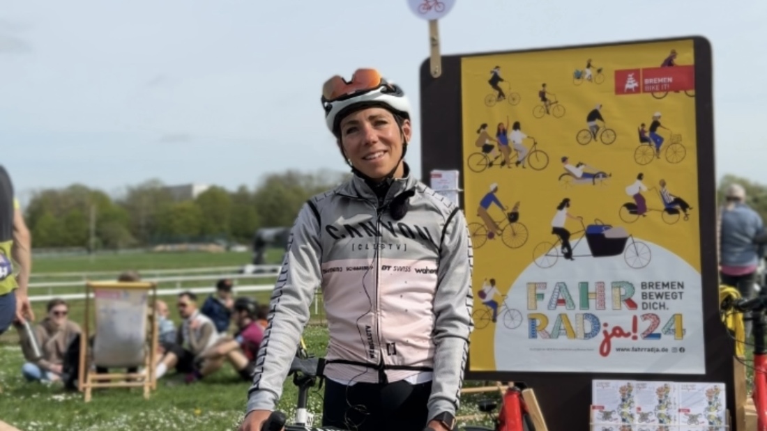 Eine Frau in Fahrradmontur steht vor einem Fahrradja-Schild