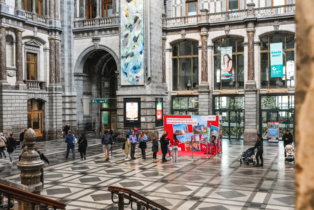 Man sieht eine große Bahnhofshalle, in der Menschen sind und ein roter Pop-up Store über Bremen steht in der Mitte