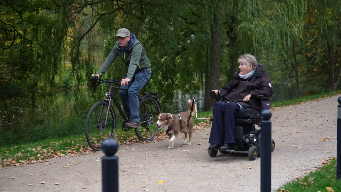 EIn Mann auf einem Fahrrad und eine Frau im Rollstuhl